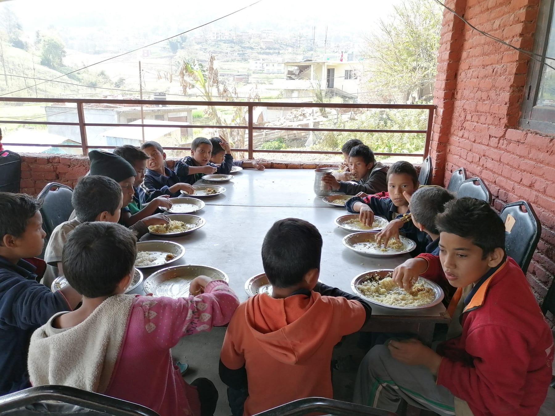 Children in Nepal sharing a meal around a long table